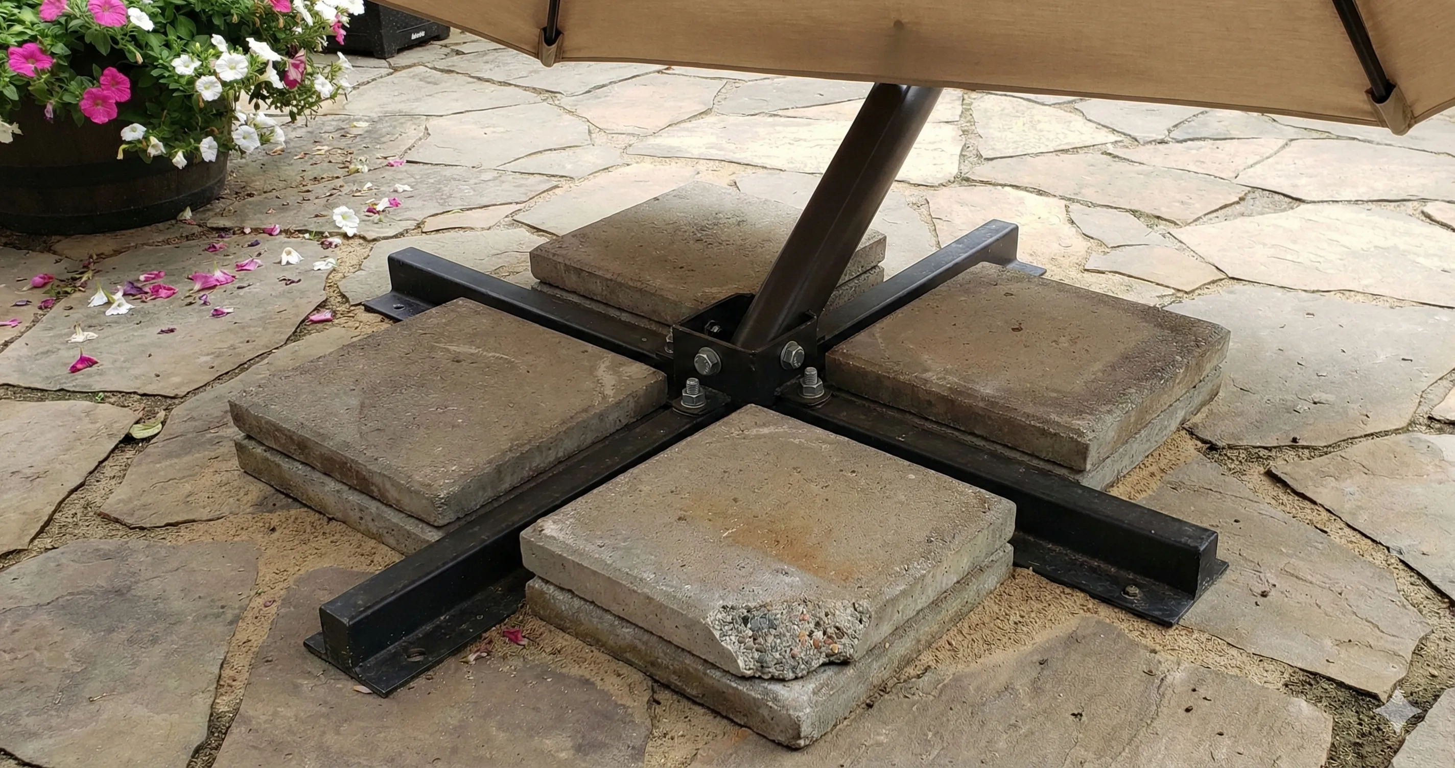Best base for offset umbrella showing heavy cross-base stand with concrete weight plates on stone patio